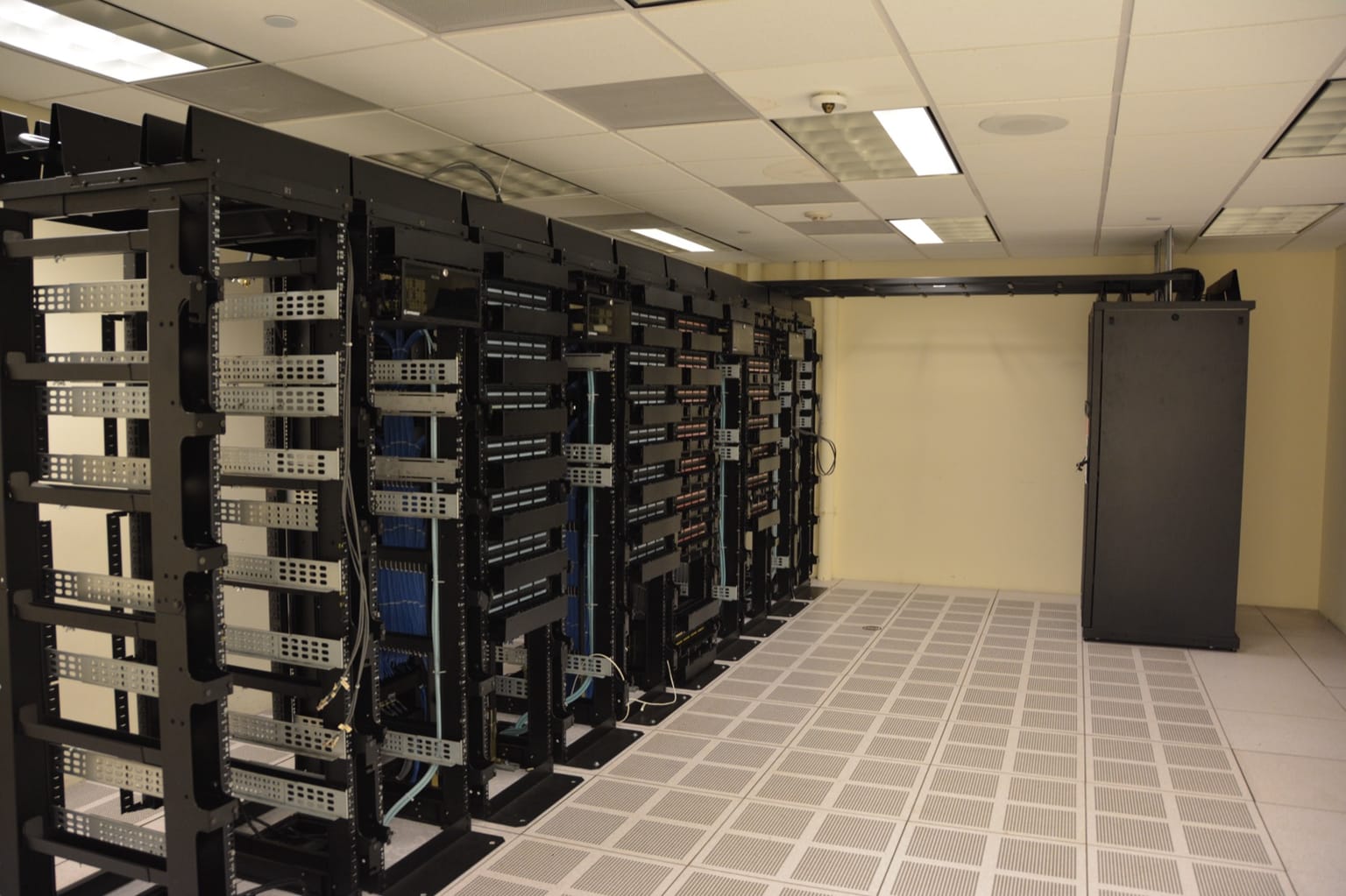 Rows of server racks in a data center, photographed by Carl Lender and used under CC BY 2.0 as the ThriveInMarkets hero for an October 5 2026 review of Steve Eisman's account of how AI cloud spending, chip receivables, and two private labs are linked
