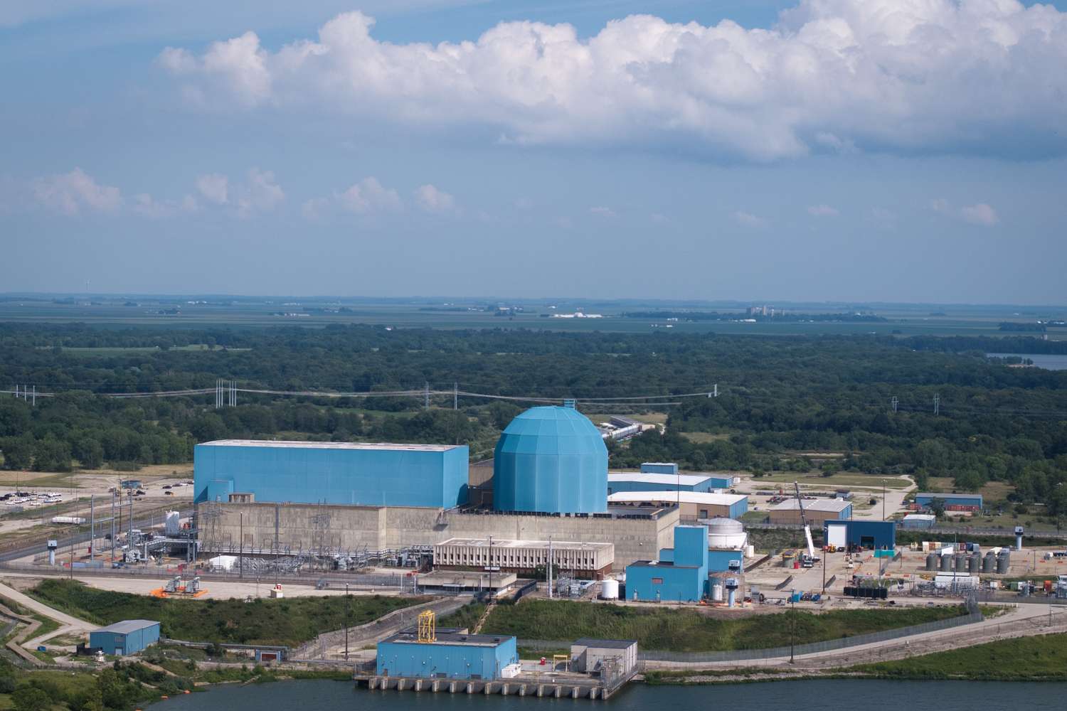 Constellation Energy's Clinton nuclear plant on a river, with a blue containment dome and turbine hall, used as the ThriveInMarkets evening-review hero for Tuesday October 6 2026, when Google contracted 3,590 megawatts from Constellation, Constellation Energy closed 300.40 dollars up 12.3 percent, and the S&P 500 closed 7,818.93 at a record