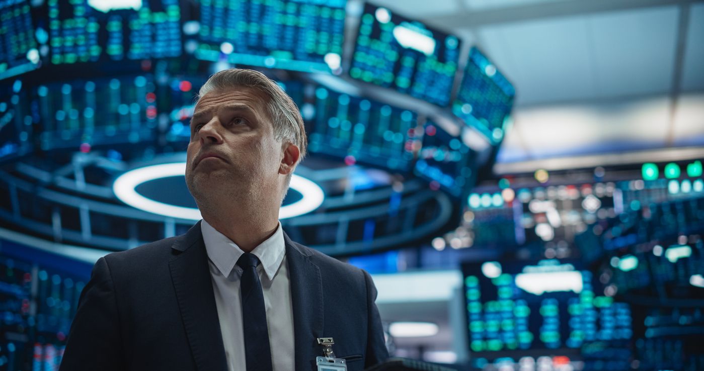 A trader on a US exchange floor looks up at quote screens, used as the ThriveInMarkets evening-review hero for Wednesday October 7 2026, when the S&P 500 closed 7,801.77 off Tuesday's 7,818.93 record and Caterpillar closed 813.83 dollars down 5.8 percent