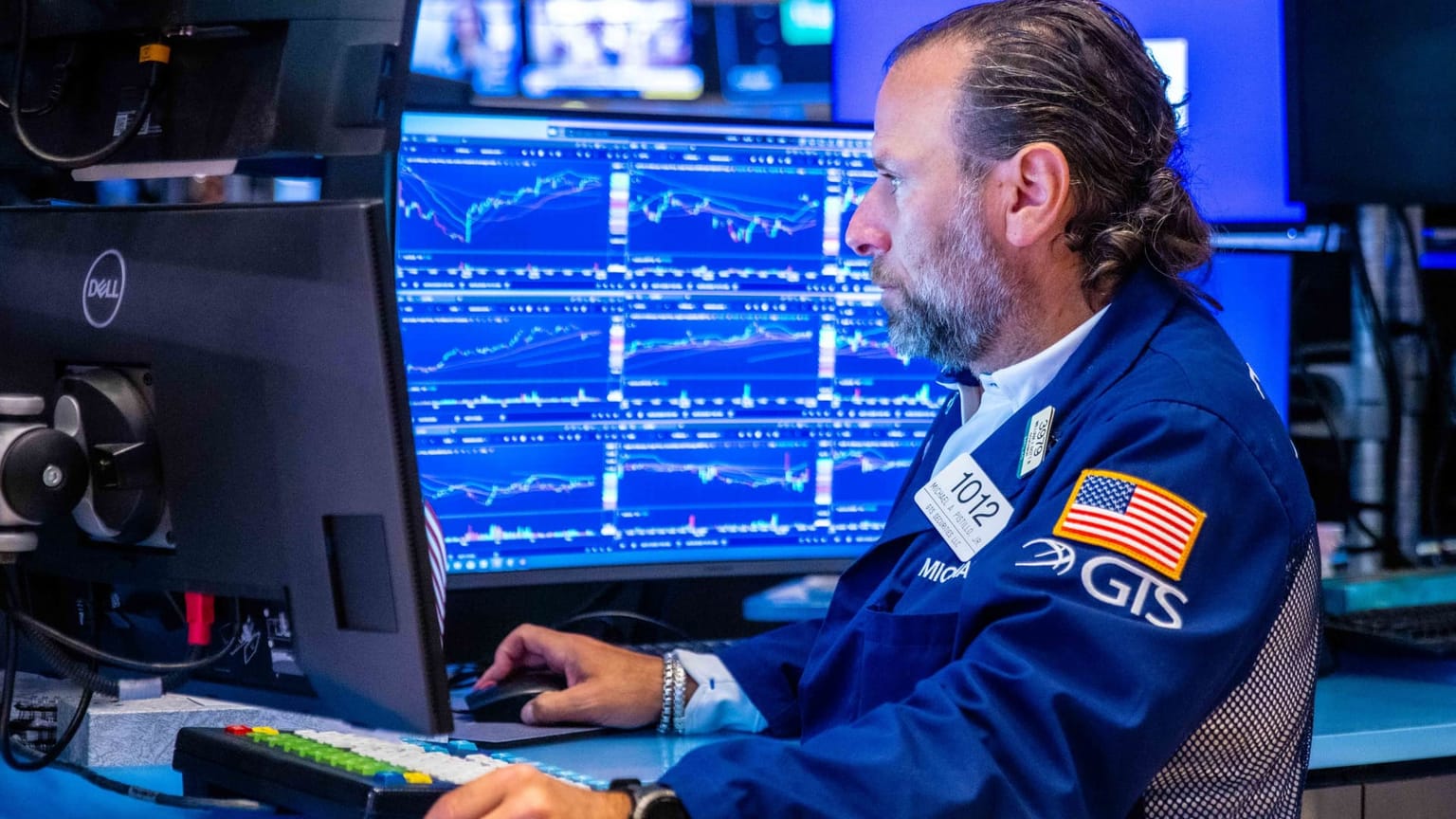 A New York Stock Exchange floor trader in a blue GTS jacket watches multi-panel charts on a Dell screen, used as the ThriveInMarkets morning analysis hero for Wednesday September 2 2026, when overnight E-mini S&P 500 futures sat near 7,635 against Tuesday's 7,631 cash close as West Texas Intermediate held the 90 dollar handle after an overnight high near 92.28 and Asian stocks tumbled on fresh US-Iran strikes