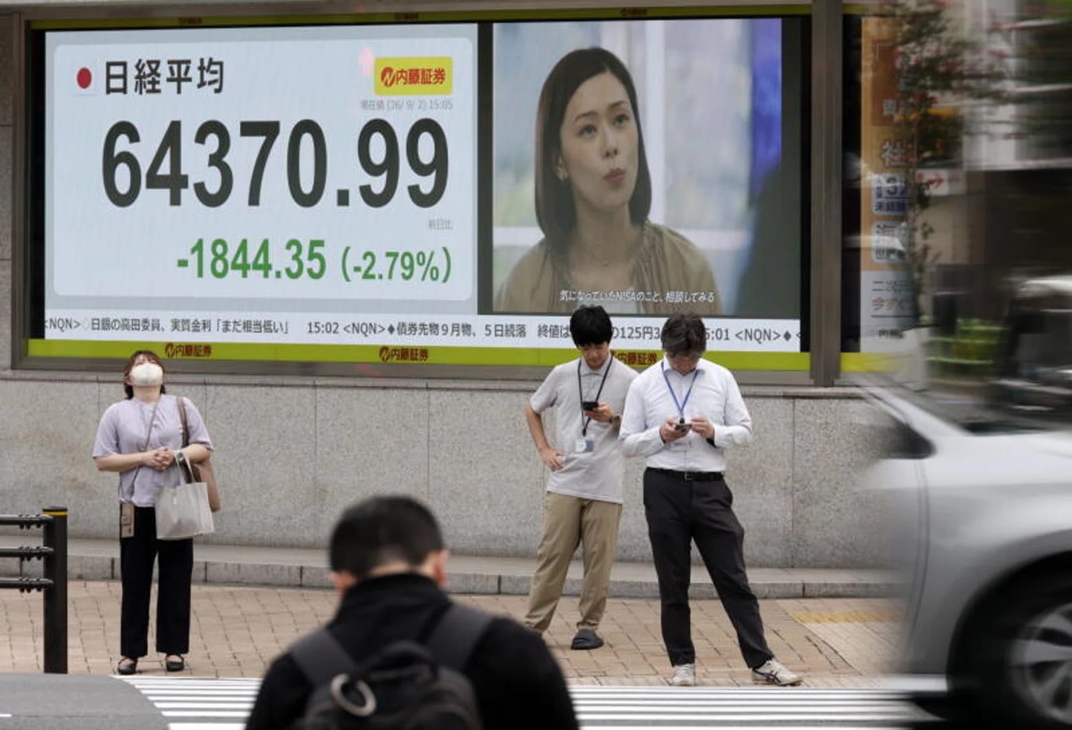 Pedestrians stand under a Tokyo street board showing the Nikkei 225 at 64,370.99, down 1,844.35 points or 2.79 percent, used as the ThriveInMarkets morning analysis inline image for Friday September 11 2026, when Japanese equities sold off as West Texas Intermediate held the 101 dollar handle after a 104.46 dollar high, Brent tagged 109.97 dollars, and overnight E-mini S&P 500 futures sat near 7,628 against Thursday's 7,591.70 cash close ahead of August CPI