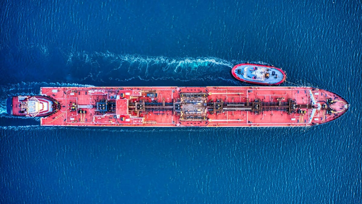 An aerial view of a red-decked crude oil tanker and a tugboat on blue water, used as the ThriveInMarkets morning analysis inline image for Friday October 2 2026, when West Texas Intermediate last printed about 91.76 dollars after Thursday's 92.87 settlement as the Pentagon added a third aircraft carrier to the Gulf and China halted October fuel exports