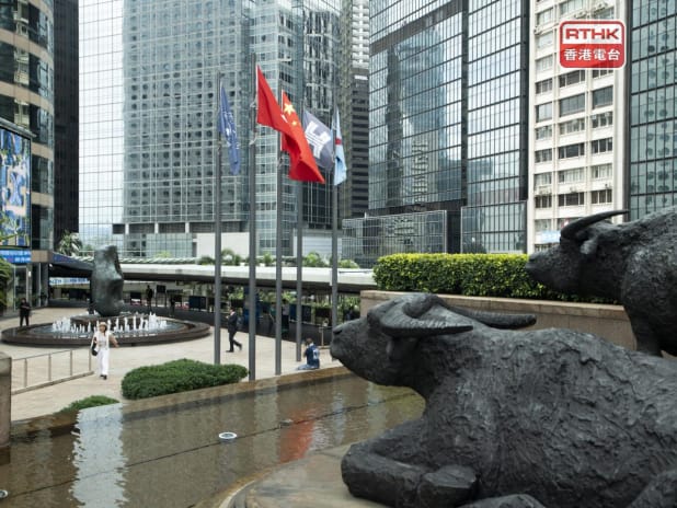 Bronze bull statues and flags of China and Hong Kong stand in Exchange Square in Central Hong Kong, used as the ThriveInMarkets morning analysis inline image for Monday October 5 2026, when the Hang Seng last printed about 23,952 in thin Golden Week trade, down 0.08 percent at midday, as mainland China stayed shut through October 7