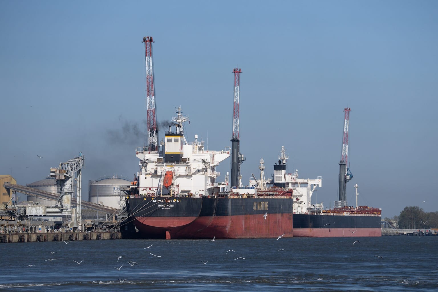 The Hong Kong-flagged tanker Darya Gayatri and a second tanker sit at a dock under red-and-white cranes, used as the ThriveInMarkets morning analysis inline image for Friday October 16 2026, when West Texas Intermediate last printed about 97.38 dollars after the IEA said it would complete remaining emergency oil releases