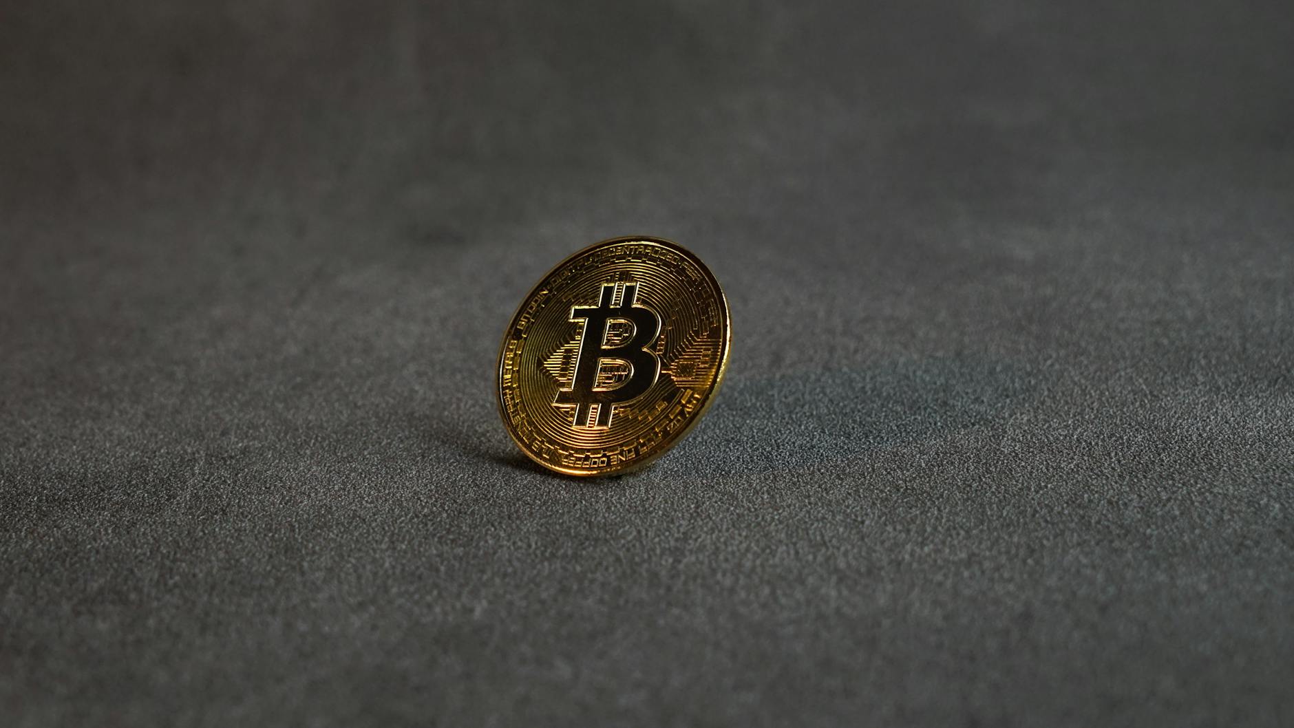 Bitcoin gold coin on dark surface representing BTC reclaiming 78000 USD level from the 75K shelf into FOMC week April 28-29 2026 with Fear and Greed at 33