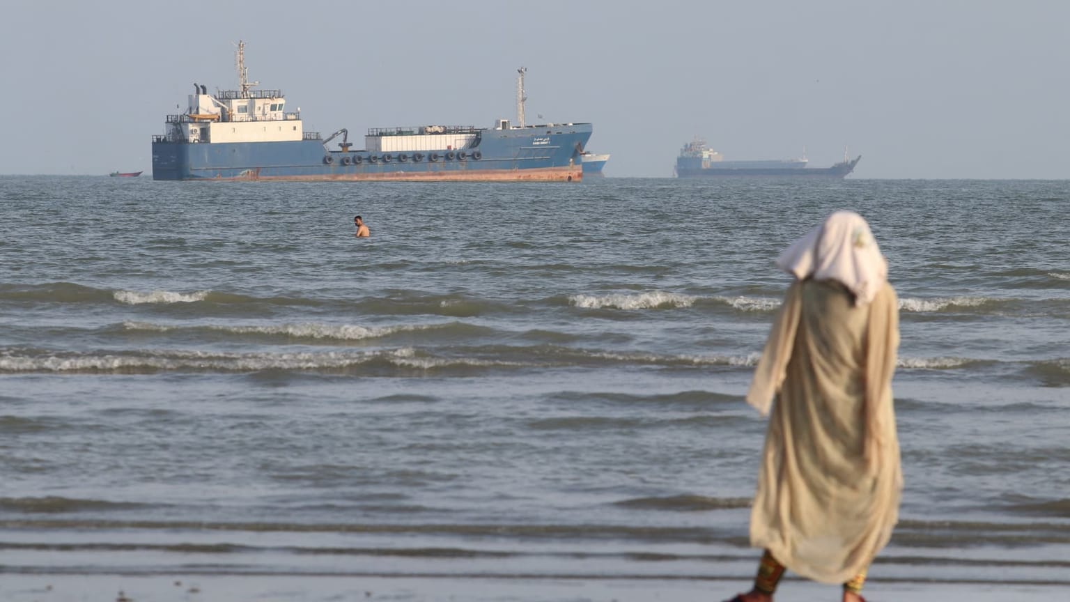 A tanker sits off a beach as a woman walks the shoreline, used as the ThriveInMarkets weekend recap inline image for October 12 to October 18 2026, when West Texas Intermediate's Friday NYMEX settlement was 101.41 dollars, up 10.4 percent on the week, and Brent tagged 110 dollars for the first time since May